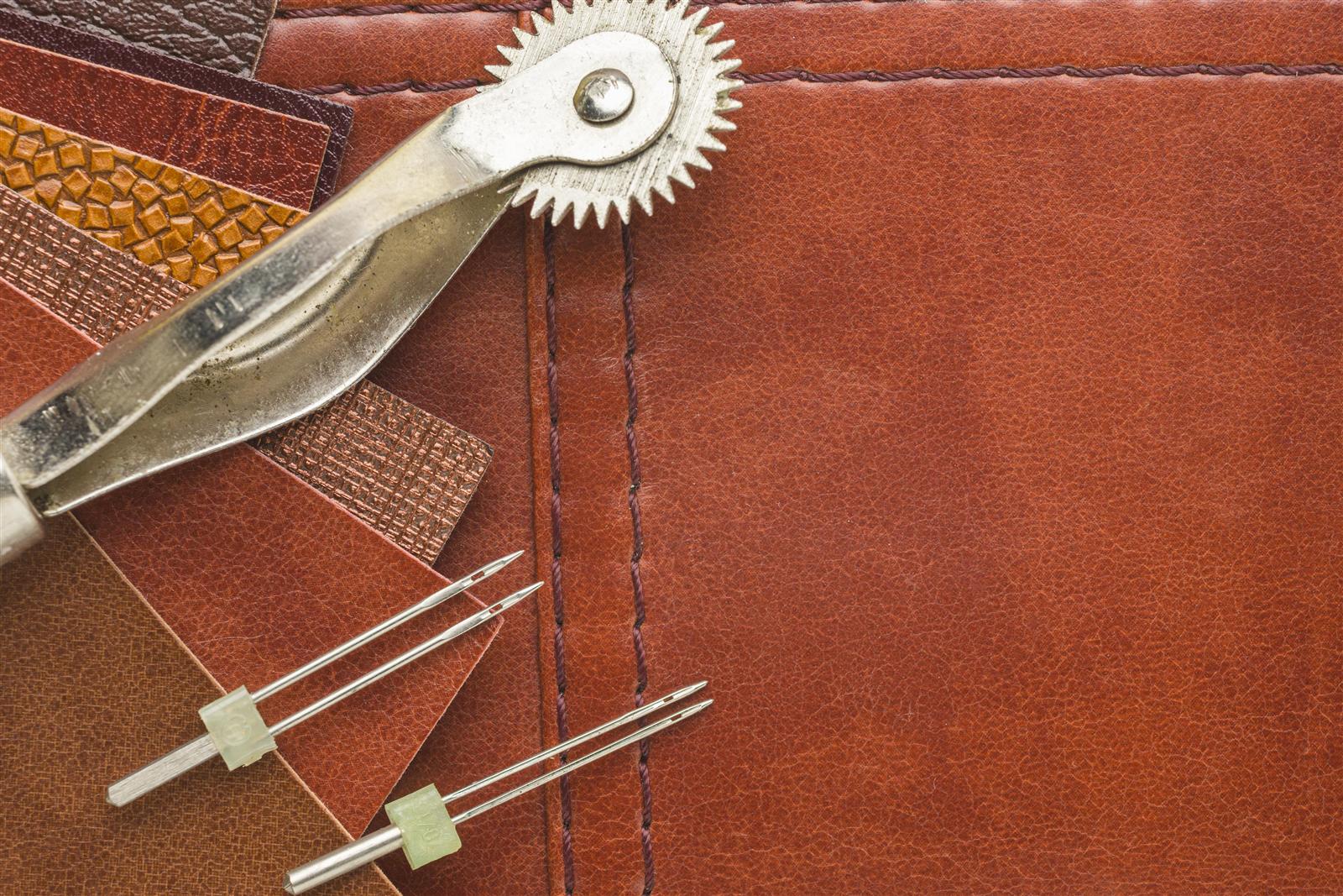 Leather samples, needles and tools laid out for inspection on a workbench