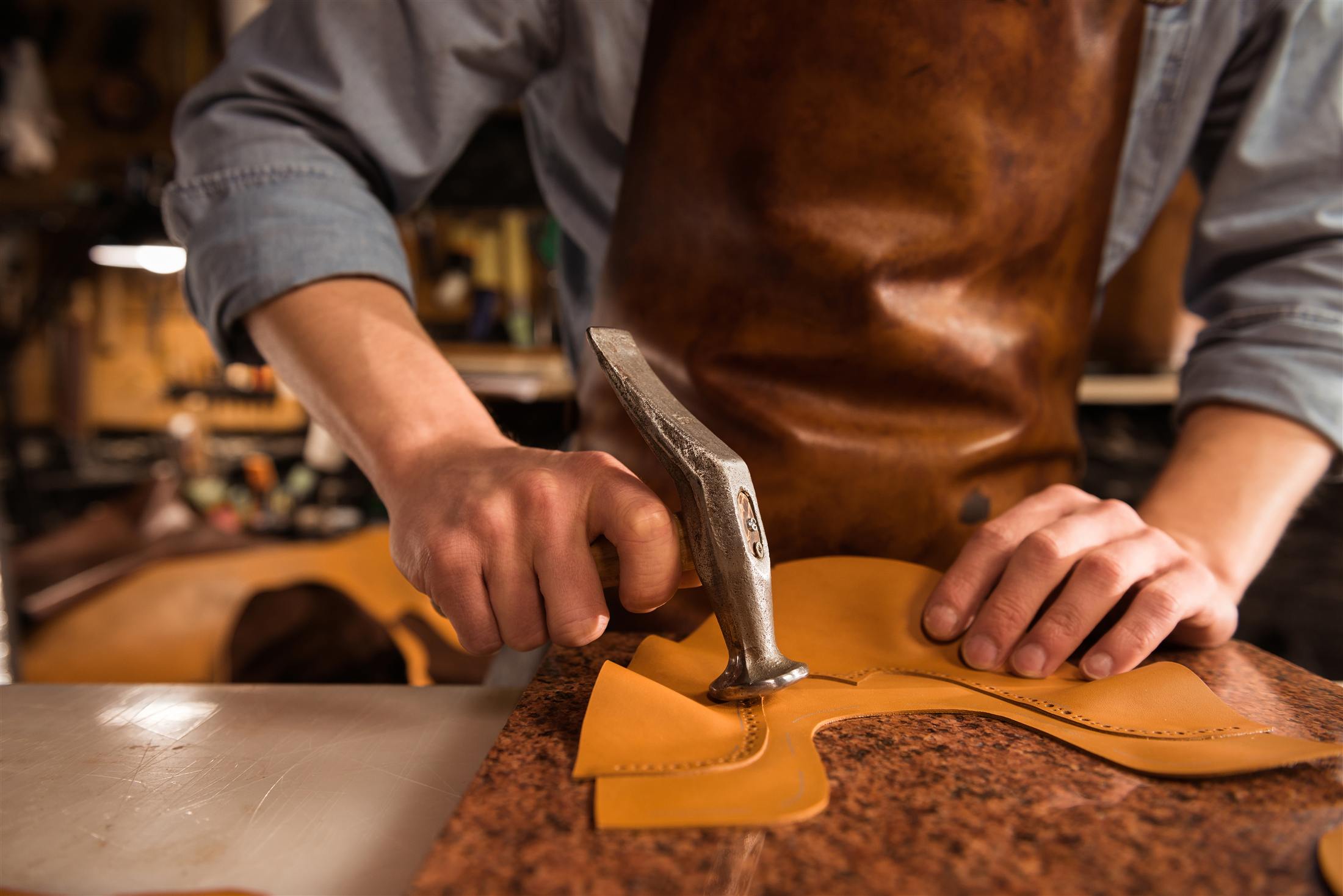 Craftsman hammering a leather piece on a workbench