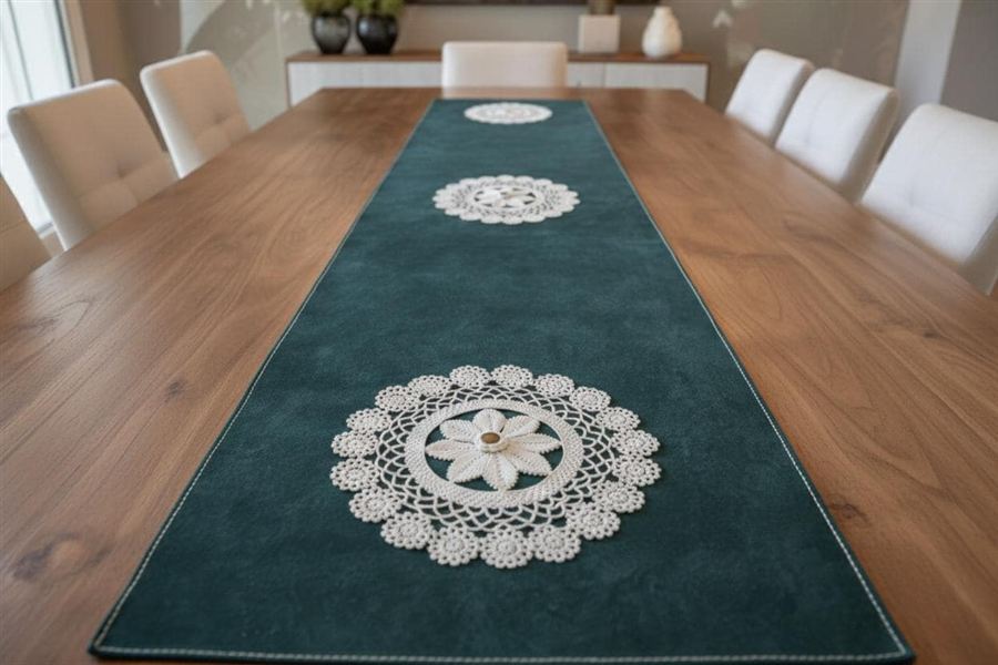 A teal Italian Pueblo leather table runner with three hand-crocheted cream lace motifs laid down the centre of a warm oak dining table