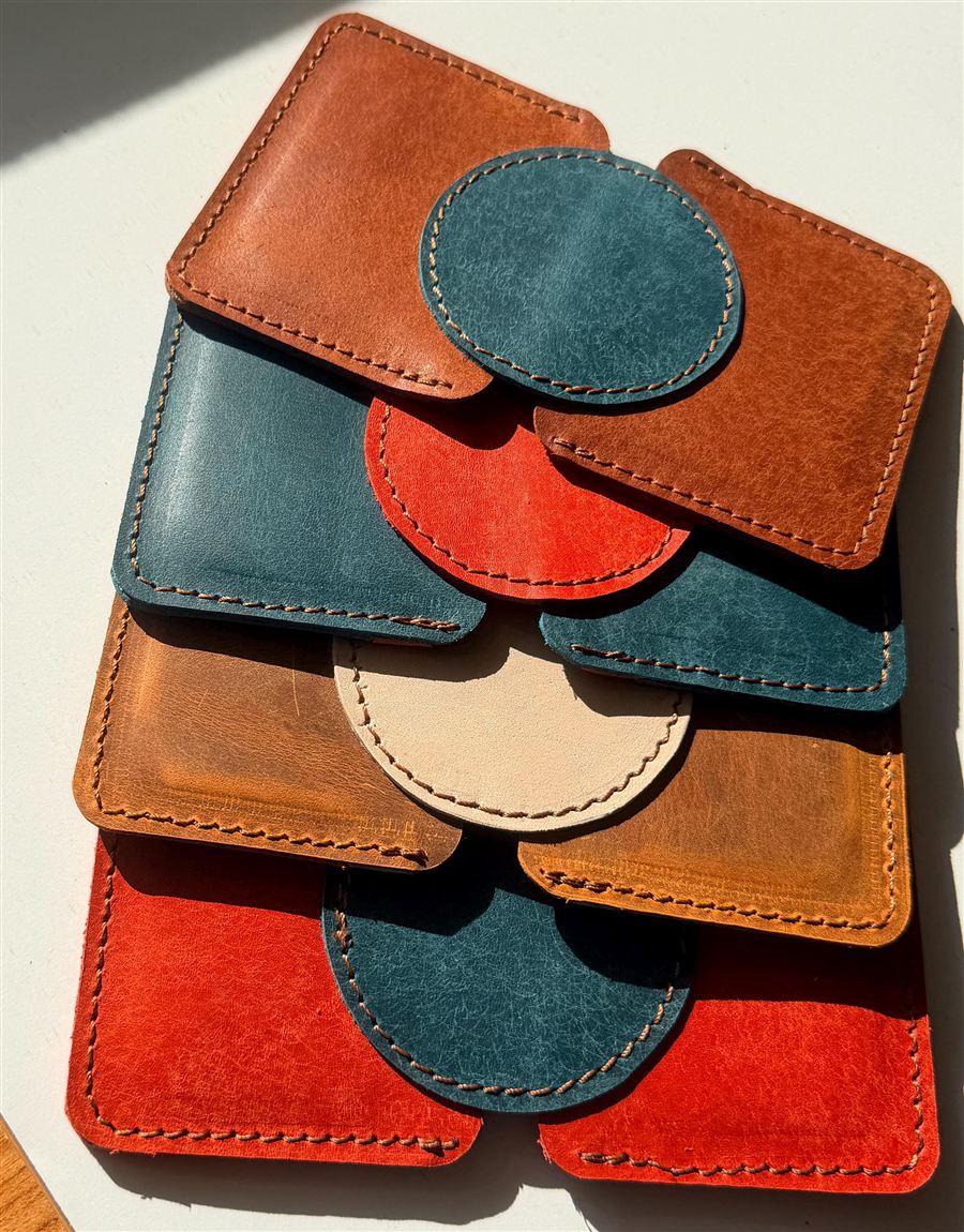 A hand-stitched Italian Pueblo leather wallet in warm tan, its matte fibrous surface catching the light, with cream saddle stitching along the edge