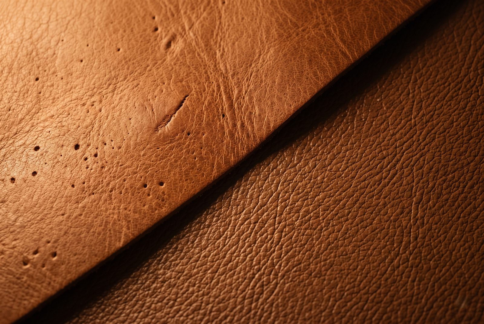 Macro comparison of natural full-grain leather with irregular pores and a healed scar against corrected-grain leather with a perfectly repeating stamped pattern