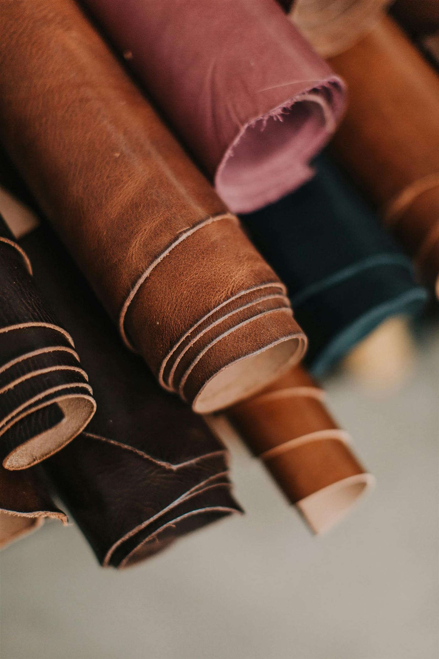 Rolled hides of vegetable-tanned leather in browns, plum and green