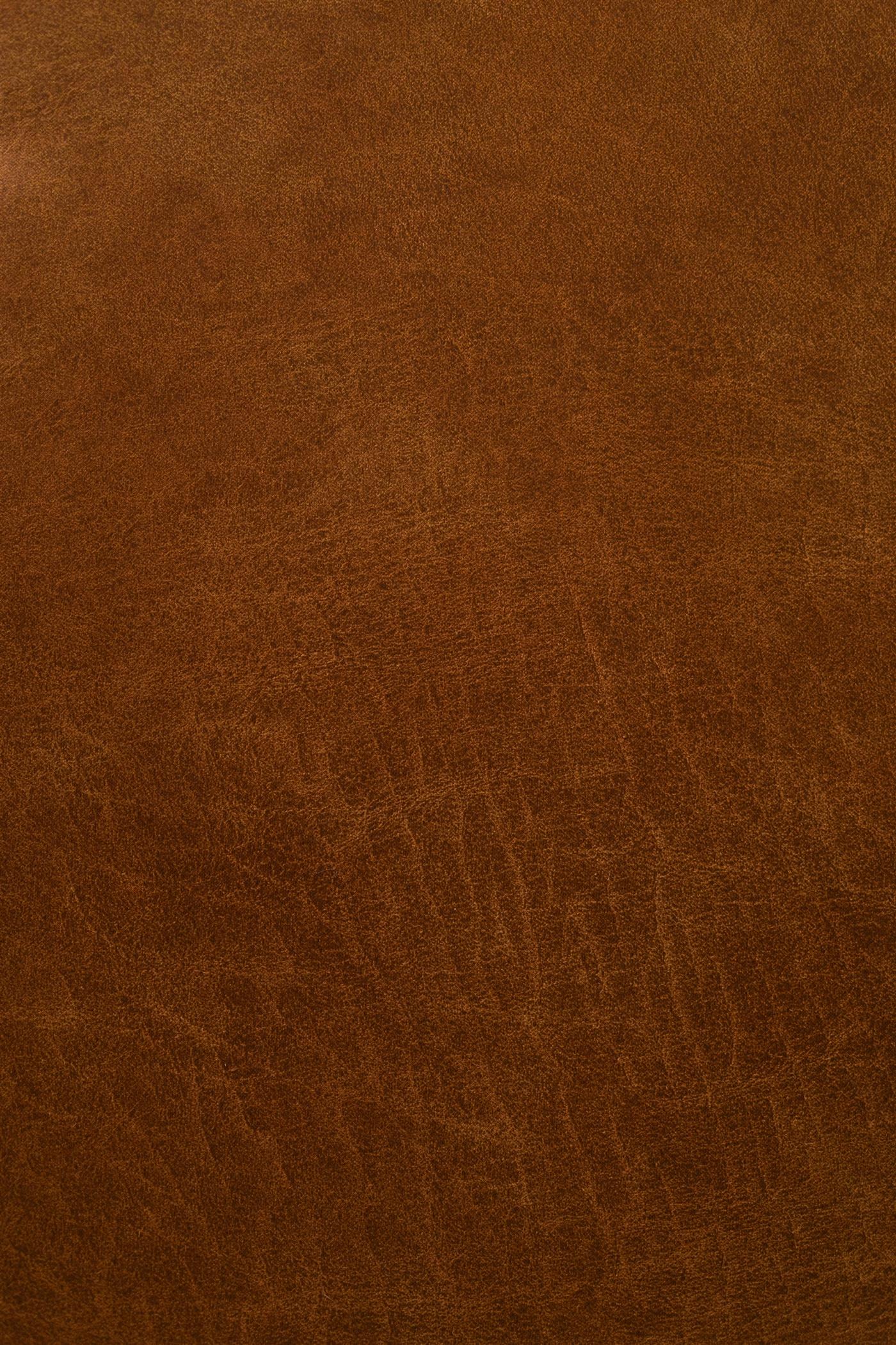 Macro photograph of a leather edge that has been skived to a feather, the pale fibrous underside tapering away to almost nothing, with a curled shaving and a bevelled skiving knife lying beside it on a cutting mat